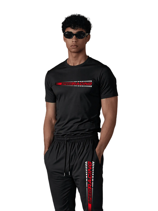 Man wearing a black t-shirt and black pants with red and white designs, standing in front of a decorative fireplace.