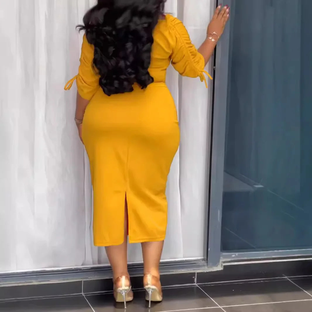 Woman in a yellow dress standing in front of a glass door.