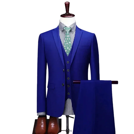 A men's three-piece suit featuring a bright royal blue blazer, matching vest, and trousers draped on a stand, styled with a green patterned tie and checkered shirt. 