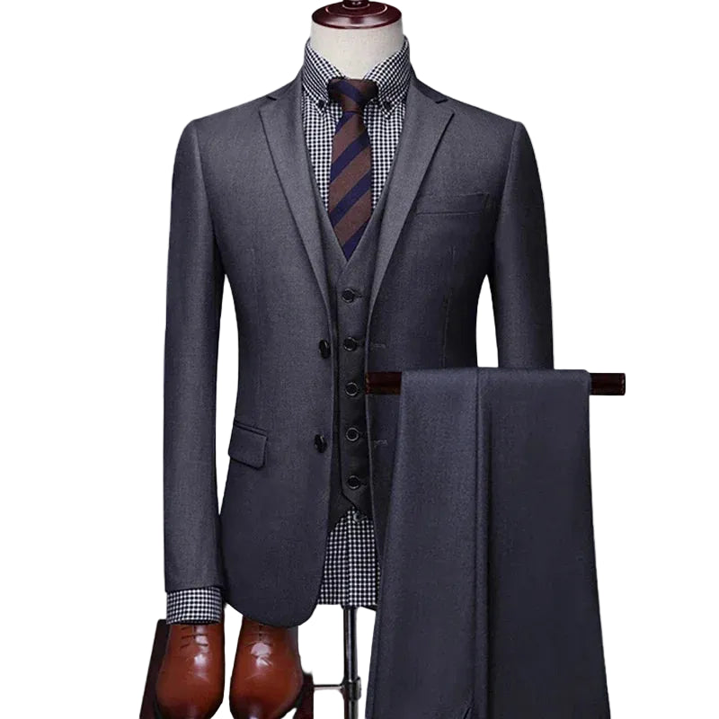 A three-piece men's suit featuring a gray blazer, matching vest, and trousers draped over a hanger, styled with a checkered shirt and striped tie.