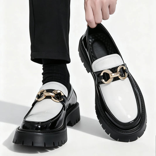 Black and white loafers with gold accents worn by a person on a white background