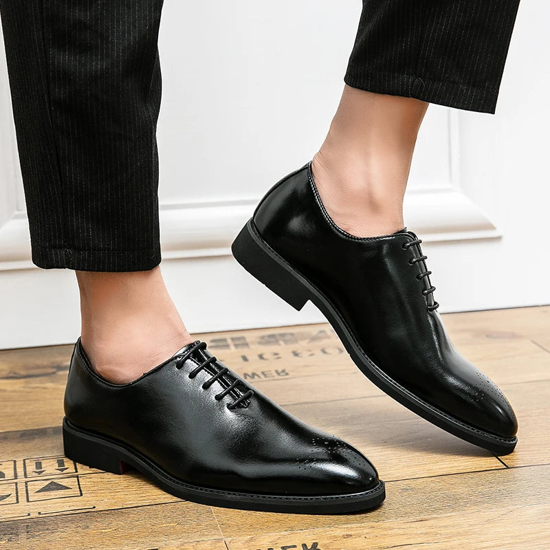 Black dress shoes worn with black pants on a wooden floor.