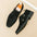 Black suede shoes with buckles on a beige surface