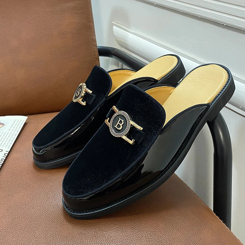 Black velvet slippers with gold accents on a brown chair.