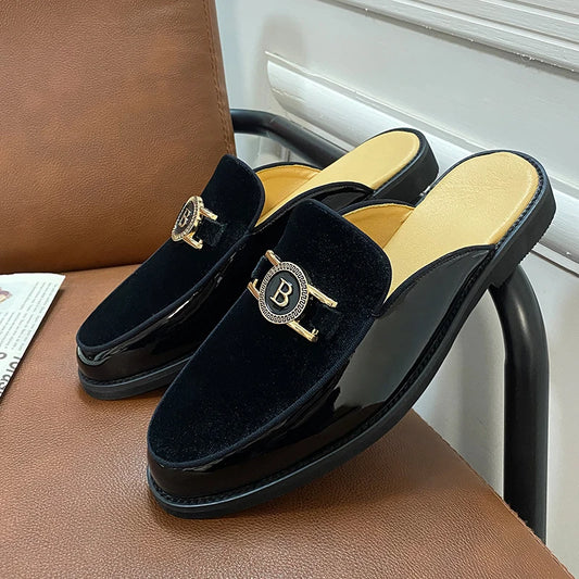 Black velvet slippers with gold accents on a brown chair.