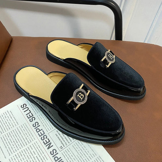 Black velvet slippers with gold emblem on a brown surface