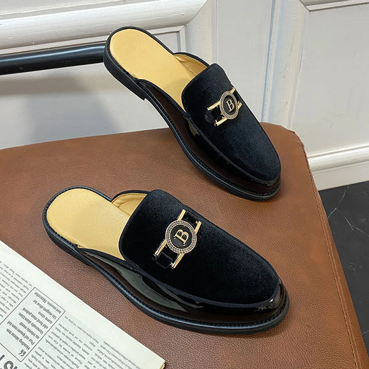 Black velvet slippers with gold emblem on a brown surface.