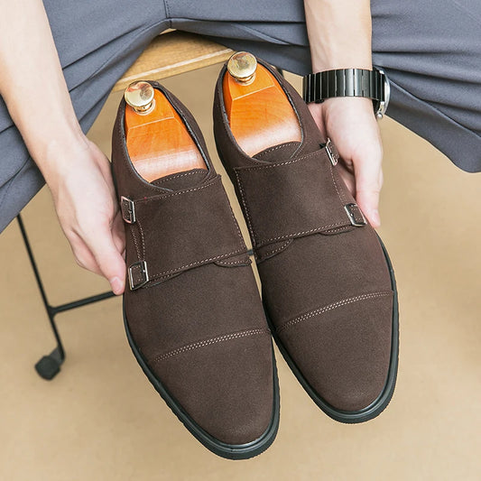Brown leather shoes held by a person with a watch on a beige floor.