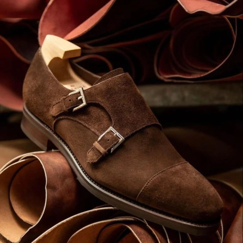 Brown suede shoe with a buckle on a background of leather pieces