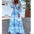 Woman wearing a blue and white patterned dress on a street with palm trees in the background