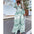Woman wearing a green floral dress on a street with palm trees in the background