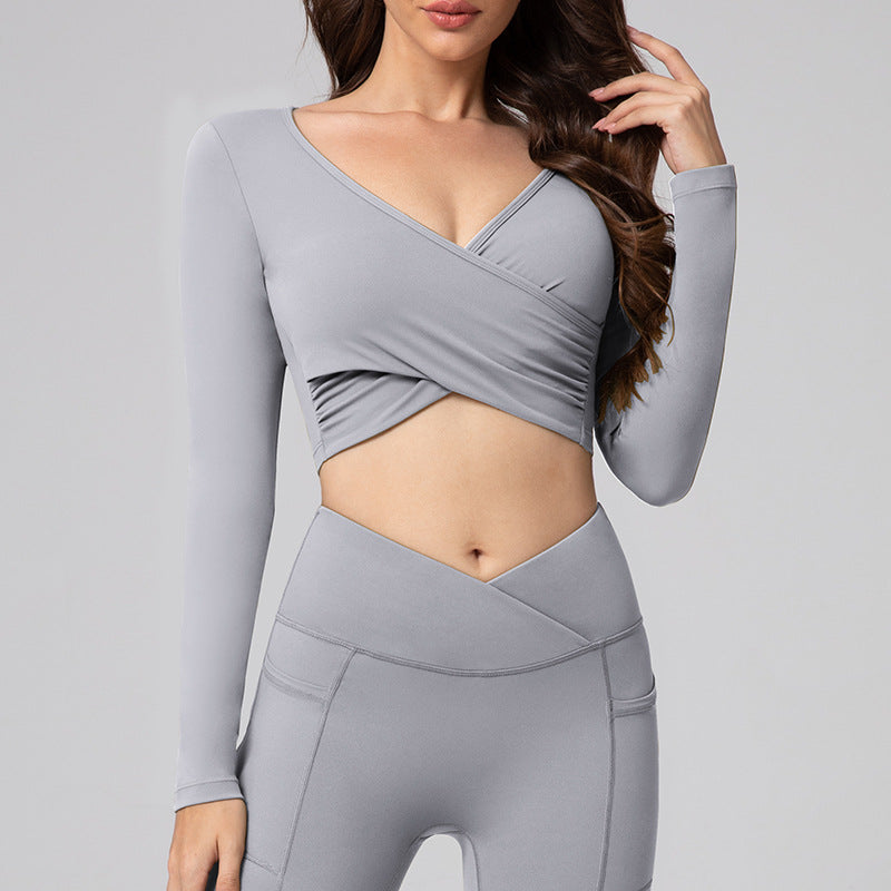Woman wearing a gray long-sleeve top and leggings on a light gray background
