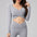 Woman wearing a gray long-sleeve top and leggings on a light gray background