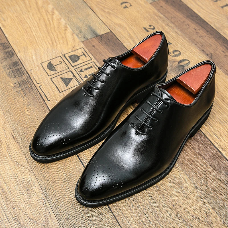 Pair of black dress shoes with orange lining on a wooden floor.