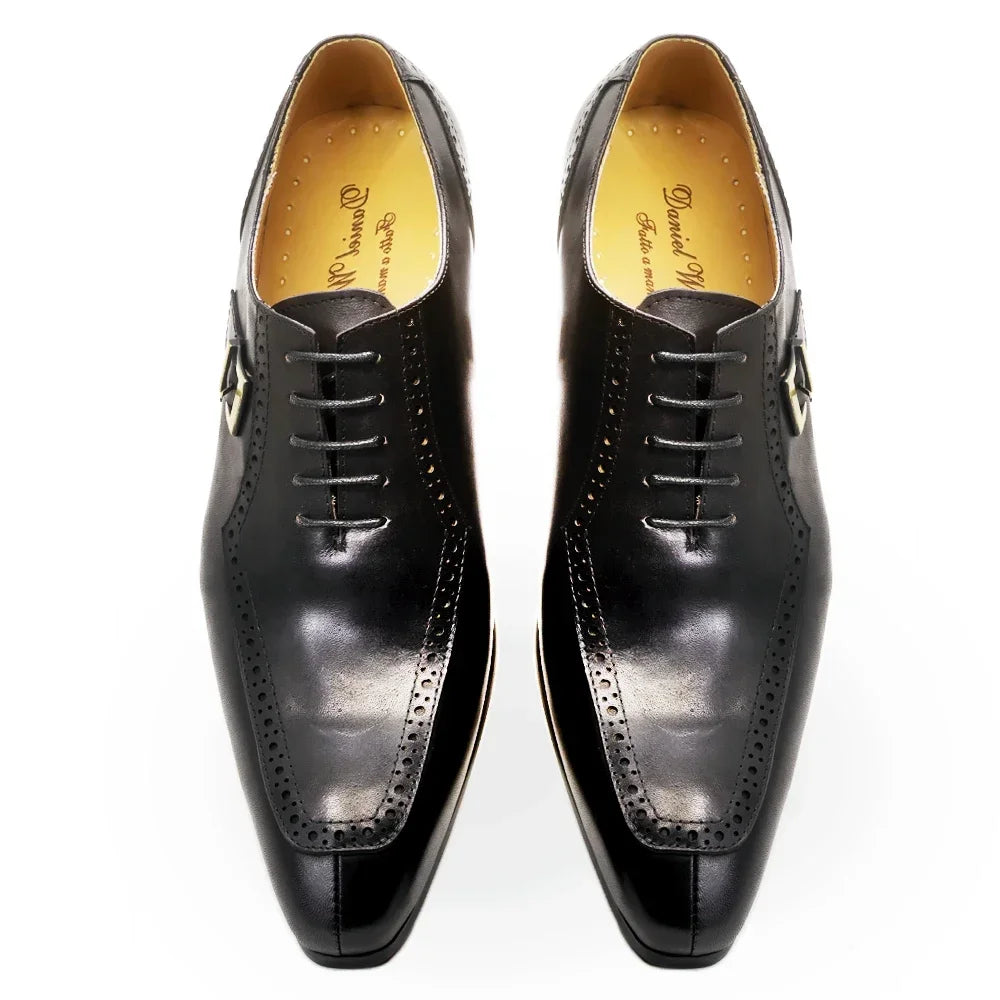 Pair of black dress shoes with gold accents on a white background