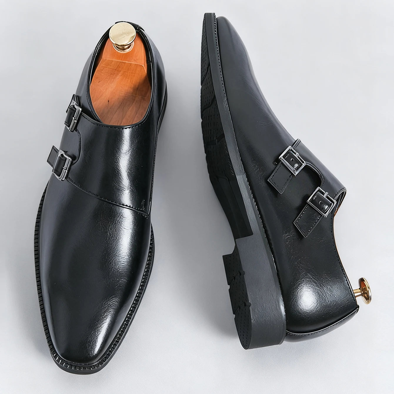 Pair of black leather shoes with buckles on a light gray background