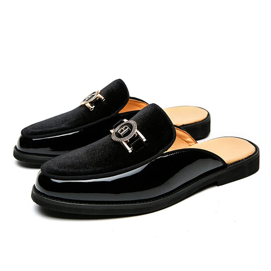 Pair of black loafers with gold accents on a white background