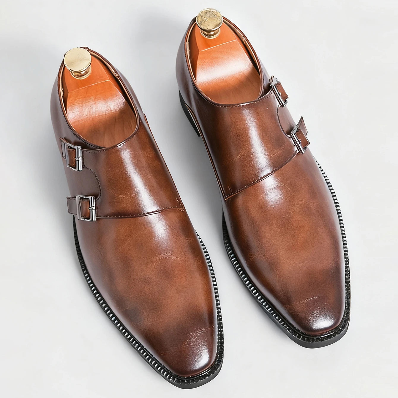 Pair of brown leather monk strap shoes on a light gray background
