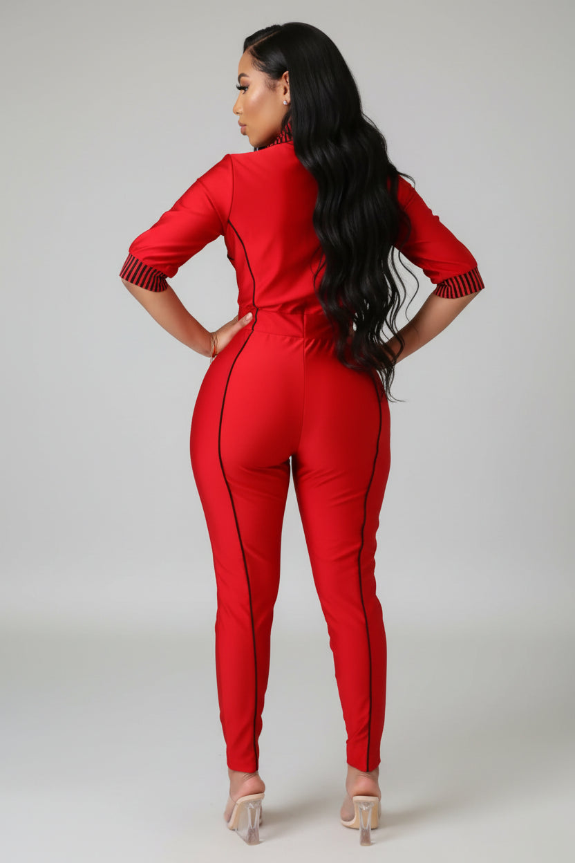Person wearing a red jumpsuit standing in a room with a mirror and shelf.