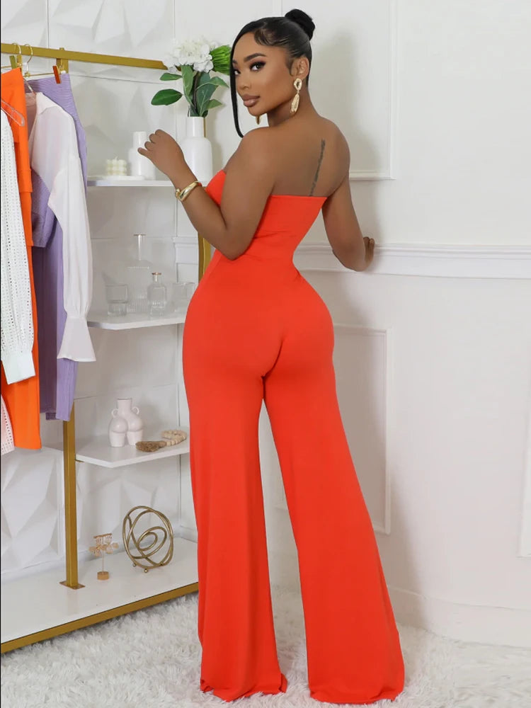 Woman wearing a bright orange jumpsuit in a room with a white wall and clothing rack.