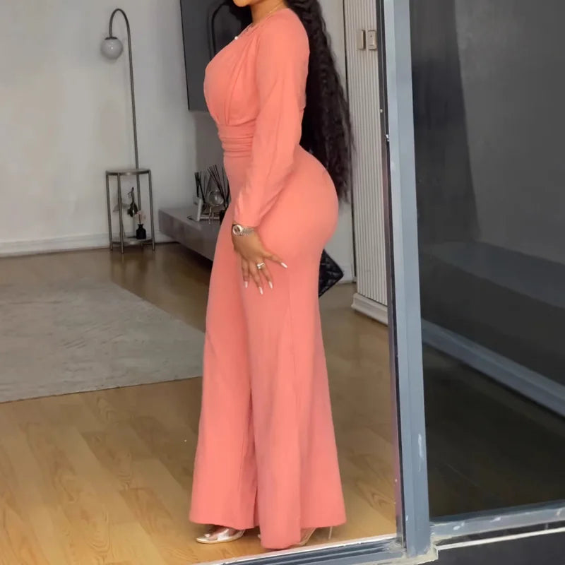 Person wearing a long pink dress standing in a room with a mirror.
