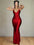 Woman in a red dress posing against a stone wall.