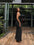 Woman in a black dress standing on a wooden deck with greenery in the background