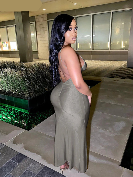 Woman in a green dress standing outdoors near a building entrance.