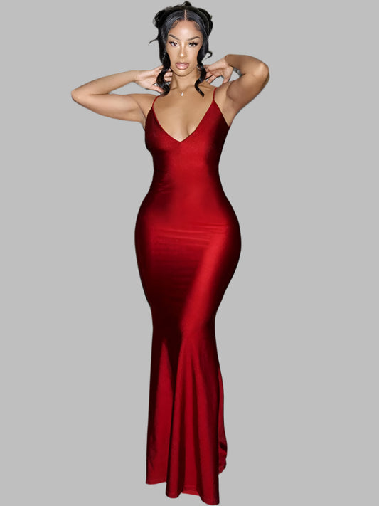 Woman in a red dress posing against a stone wall.