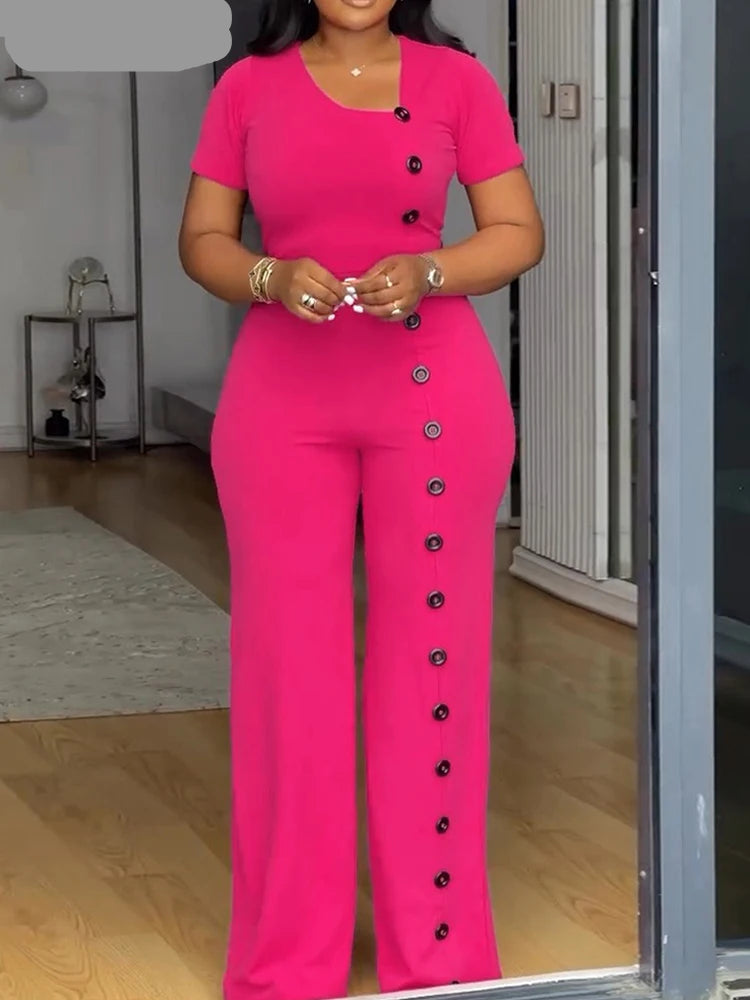Woman wearing a bright pink outfit with black buttons in a room.