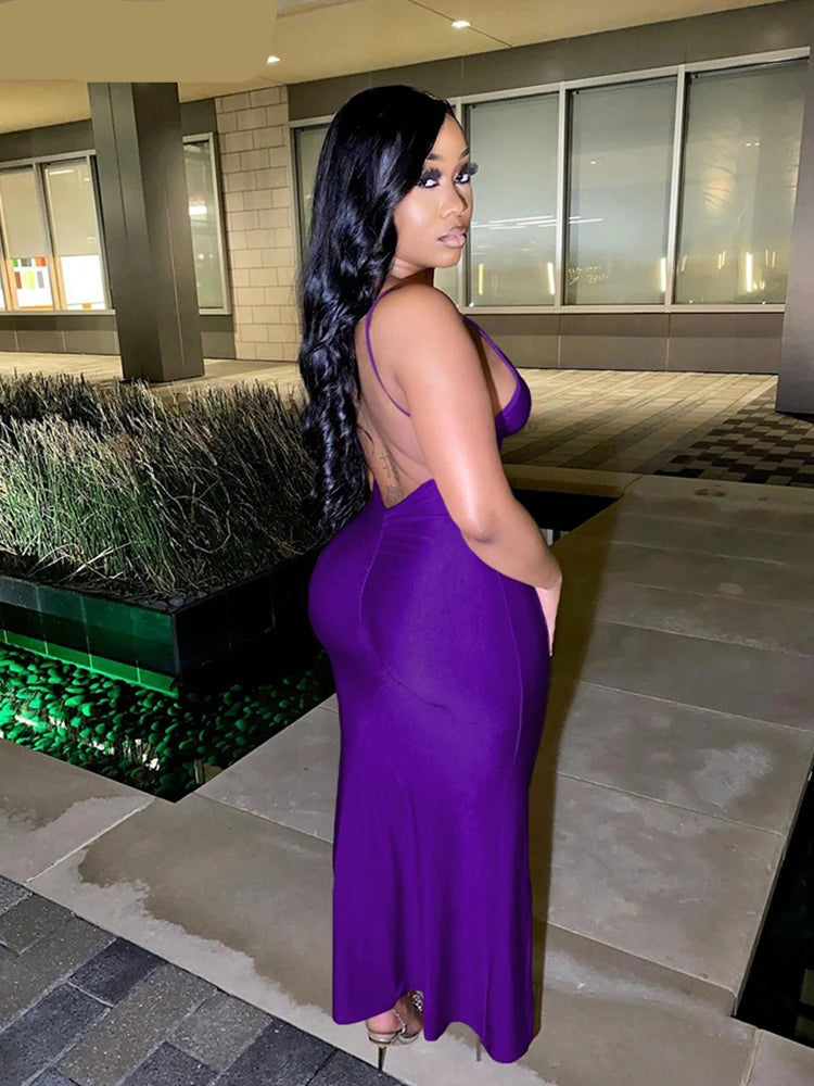 Woman in a purple dress standing outdoors near a building entrance.