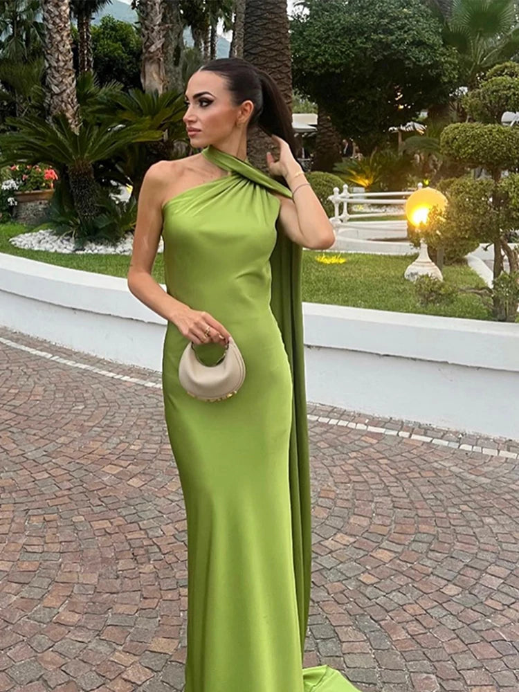 Woman in a green evening gown standing outdoors with a garden background