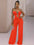 Woman wearing a bright red jumpsuit in a room with a white wall and clothing rack.