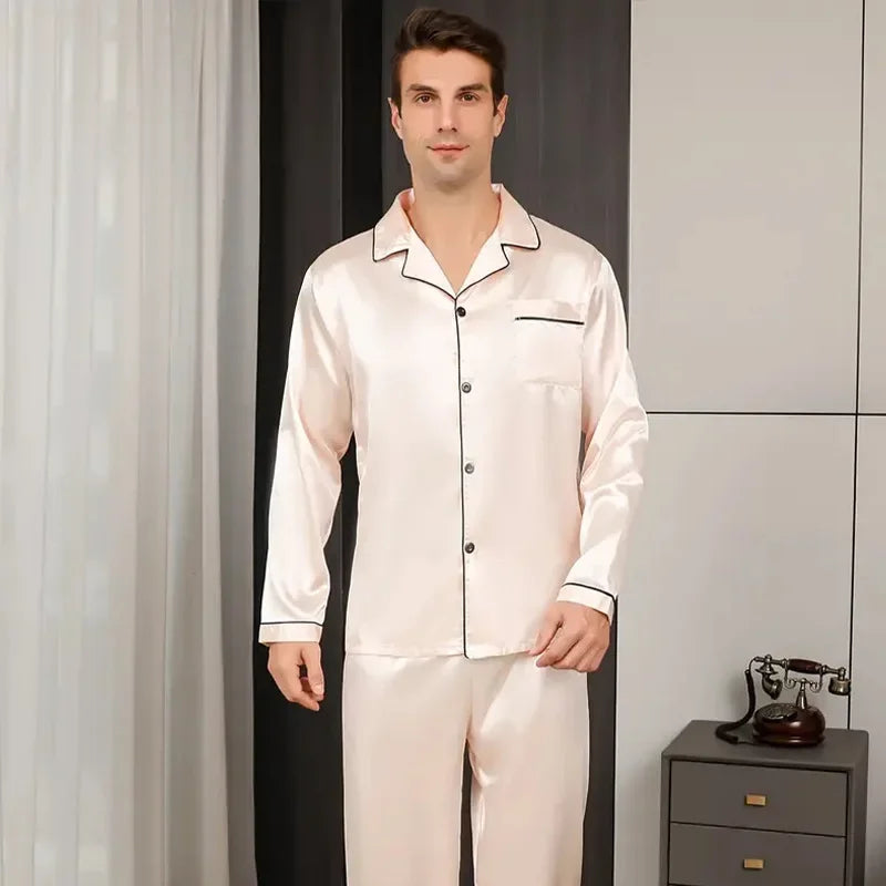 Man wearing a white satin pajama set in a room with a phone on a table.
