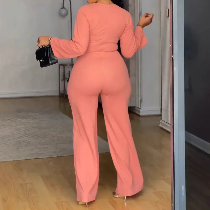 Person wearing a pink jumpsuit standing in a room.