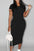 Woman in a black dress holding a white handbag on a city street.