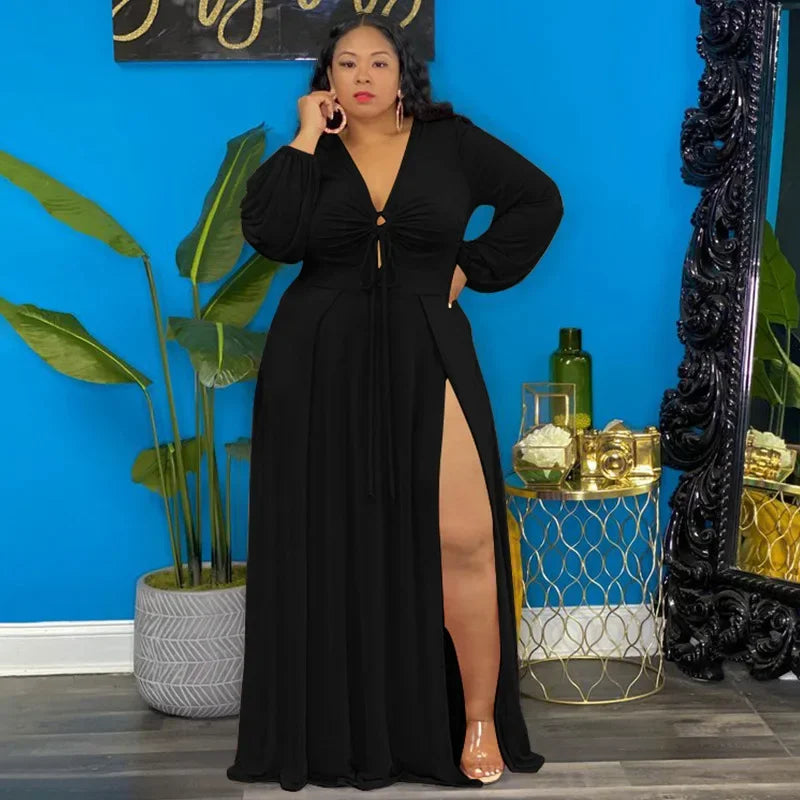 Woman in a black evening gown standing in a room with blue walls, plants, and decorative items.
