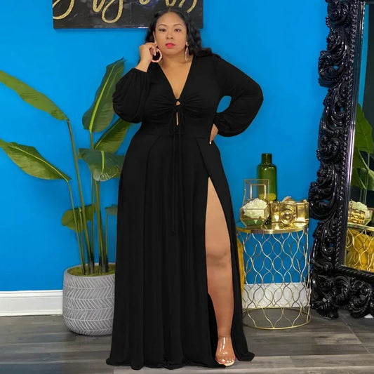 Woman in a black evening gown standing in a room with blue walls, plants, and decorative items.