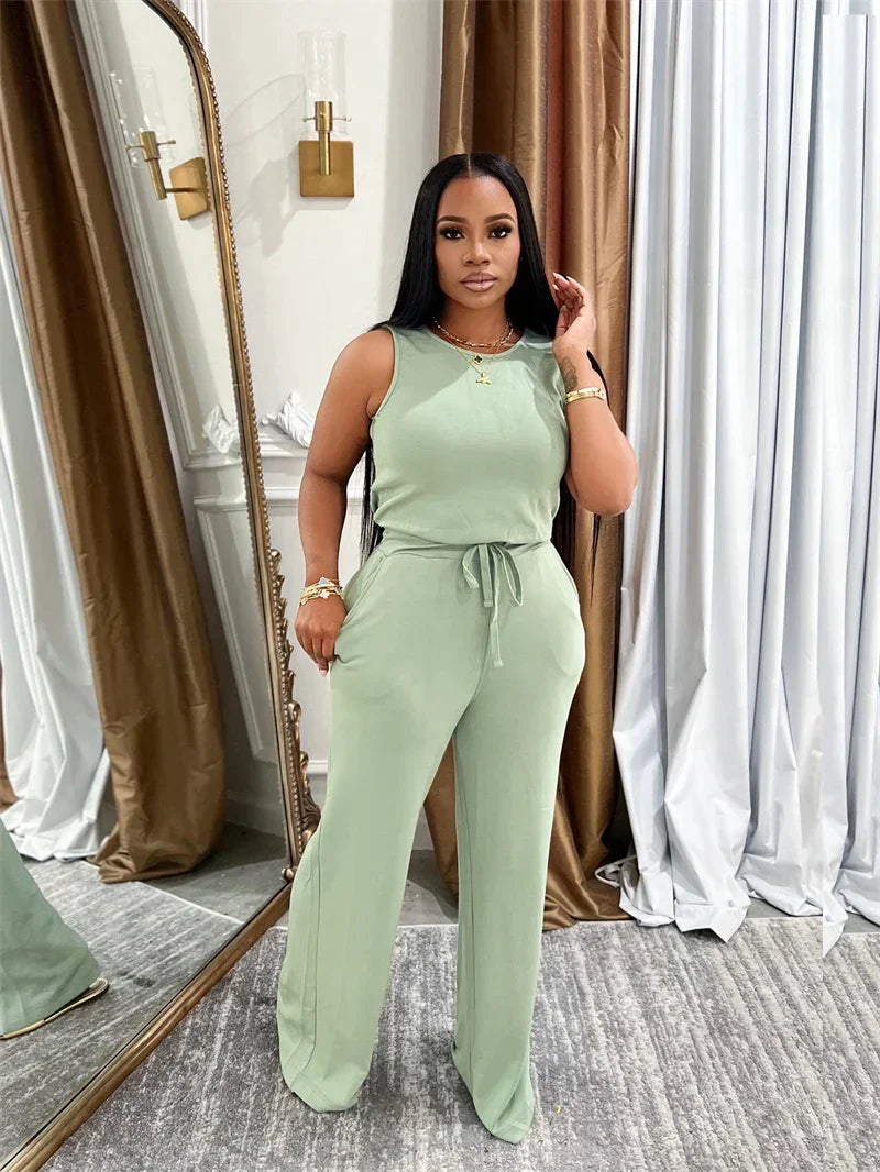 Woman in a light green jumpsuit standing in front of a mirror.