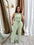 Woman in a light green jumpsuit standing in front of a mirror.