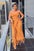 A woman in a mustard yellow fringe dress standing on a balcony.