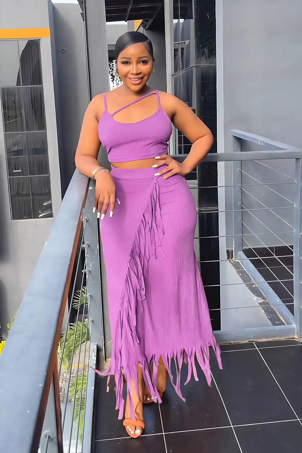 Woman in a purple fringe outfit standing on a balcony.