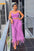 Woman in a purple fringe outfit standing on a balcony.