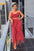 Woman in a red fringe outfit standing on a balcony