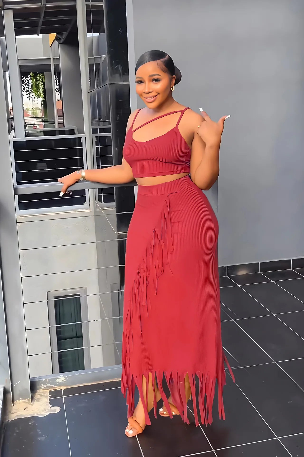 Woman in a red fringe dress standing in an outdoor setting.