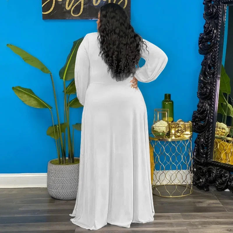 Woman in a white dress standing in front of a blue wall with decorative elements.