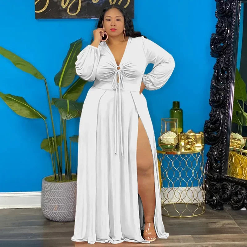 Woman in a white dress standing in a room with a blue wall, plants, and decorative items.