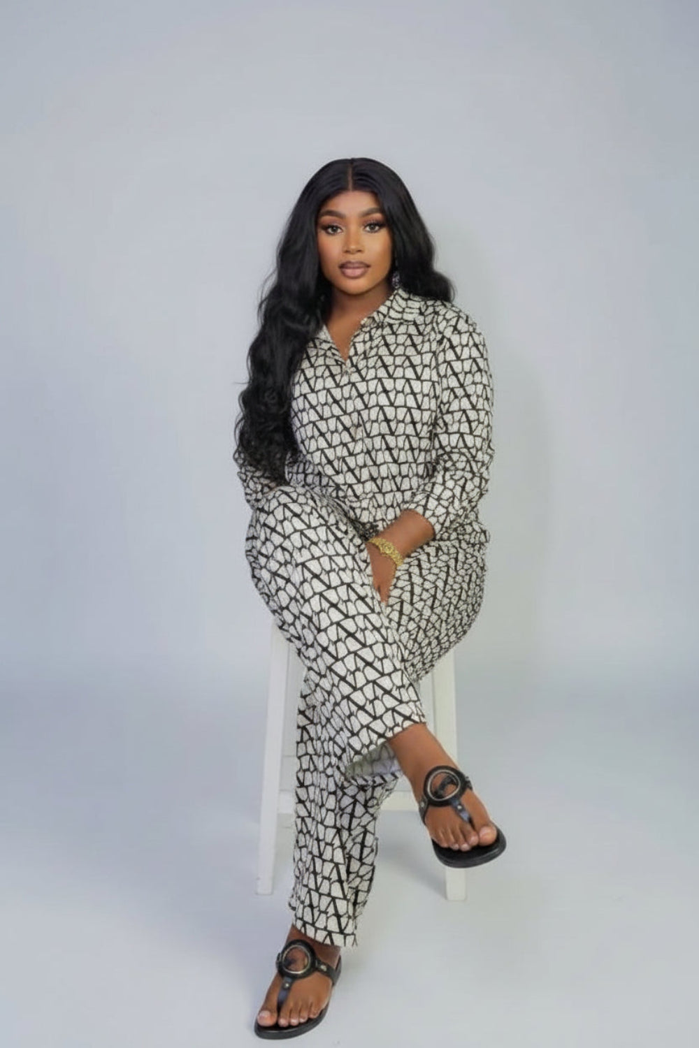 A woman in a patterned outfit is sitting on a brown leather couch with 'Joskaa' branding.