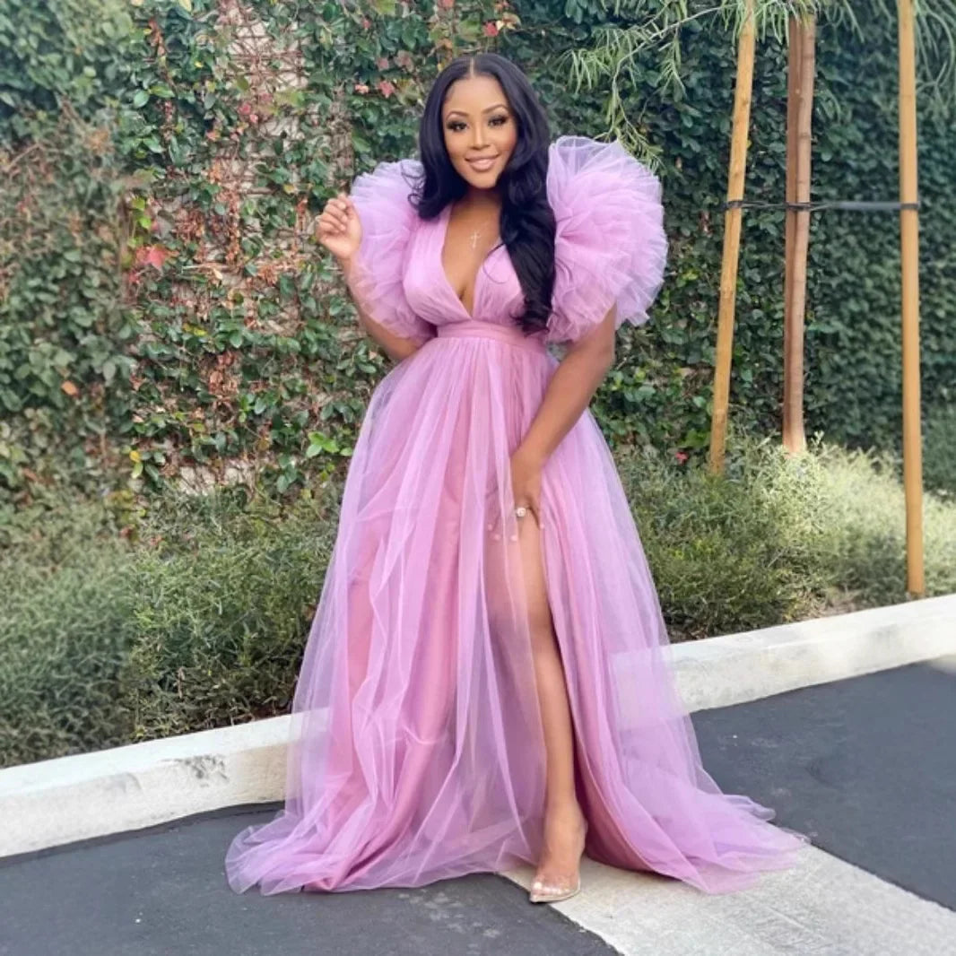 Woman in a pink evening gown with puffed sleeves standing outdoors.