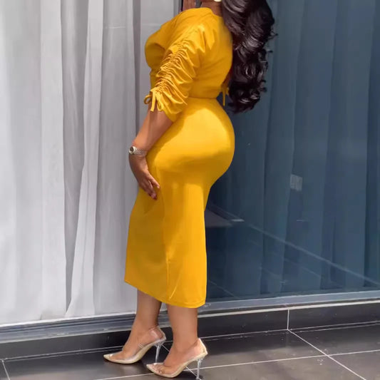 A woman wearing a yellow dress is standing in front of a glass door.